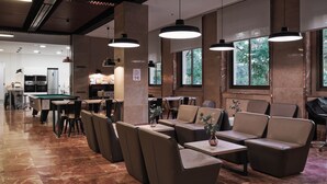 Un espace de restauration intérieur moderne, doté de hauts plafonds, de luminaires suspendus et de grandes fenêtres.