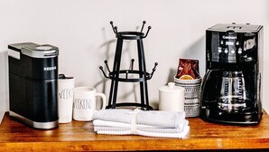 A coffee bar setup with a Keurig coffee maker, a Cuisinart coffee maker, and a coffee mug rack.