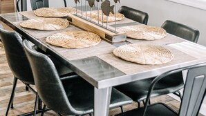 A dining table with woven placemats, black chairs, and a decorative fish sculpture centerpiece.