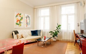 Relax in this stylish living room with a sofa, coffee table, dining table, and potted plant.