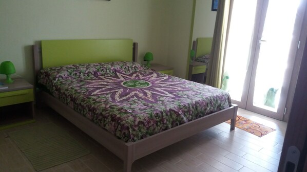 A bedroom with a bed, green nightstands, and a window with a view. - L'Arcobaleno Di Chia (Domus de Maria)