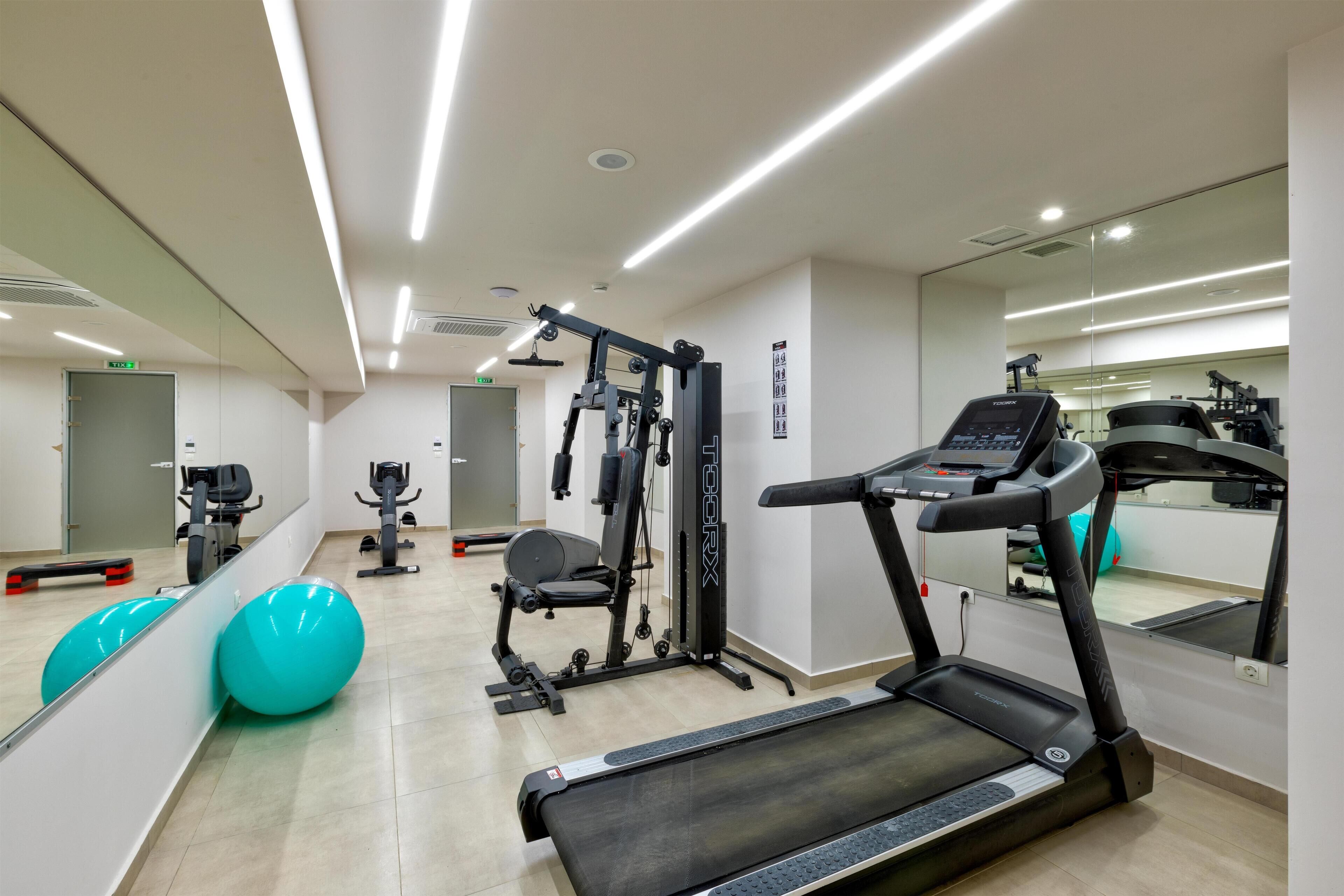 Een moderne sportschool met trainingsapparatuur, een loopband en spiegelwanden.