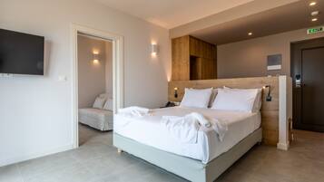 A modern hotel room with a large bed, a TV mounted on the wall, and a wooden headboard.