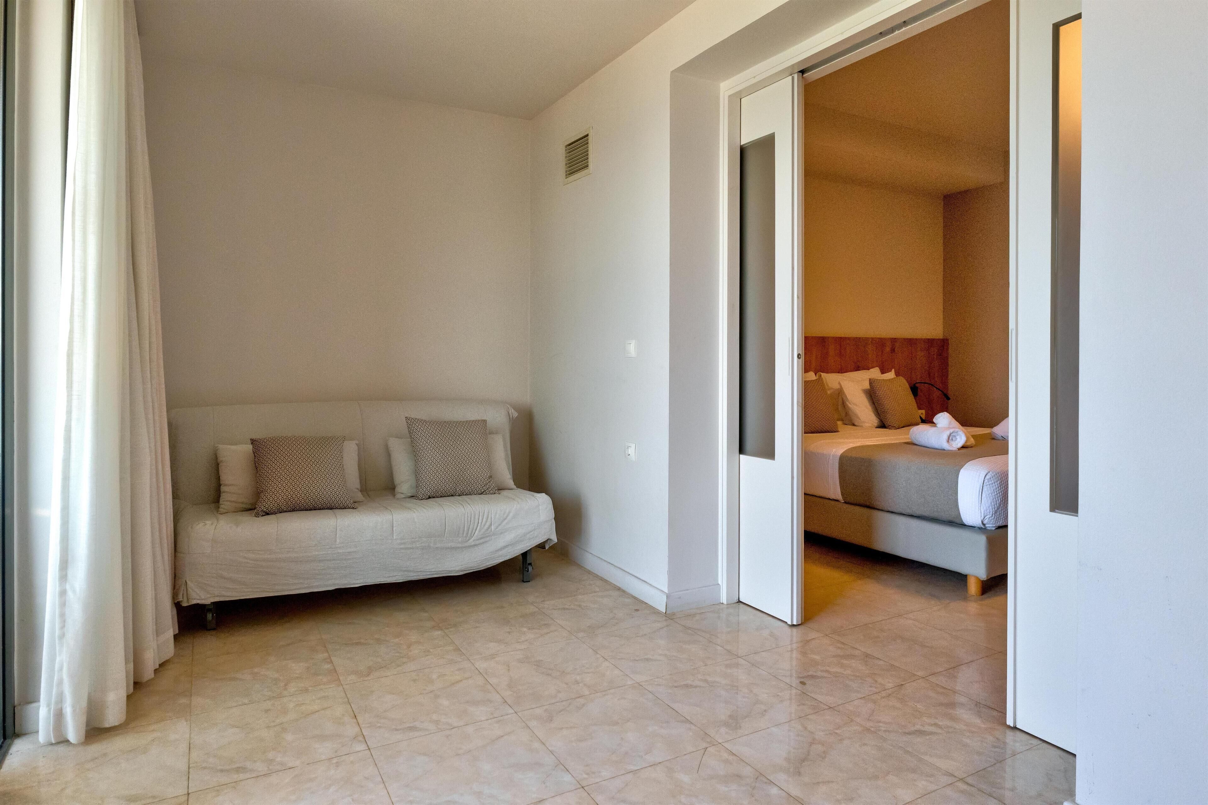 Una camera d'albergo con un letto, un divano e un bagno visibile attraverso una porta aperta.