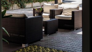 Un área de estar al aire libre techada con muebles de mimbre y una planta en maceta.