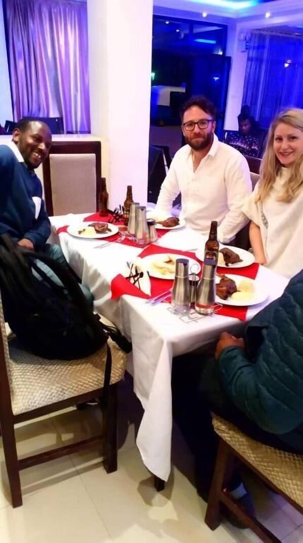 A dining area with a table set for four, featuring a white tablecloth, red napkins, and metal condiment holders. - Tsehay Zeleke Hotel (Debark)