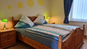 A wooden bed with a blue and white striped bedspread, two bedside lamps, and a nightstand with a lamp.