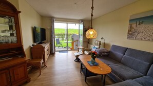 A living room with a wooden cabinet, a television, a sofa, and a dining table.
