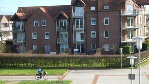 A residential building with multiple balconies and a paved area with a cyclist.