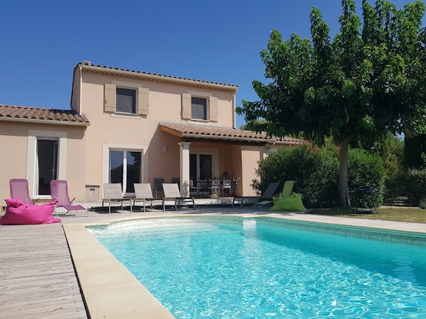 Relax by the pool surrounded by a wooden deck and lounge chairs.