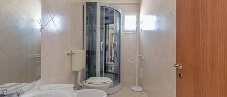 A bathroom with a bathtub, toilet, and a glass-enclosed shower stall.
