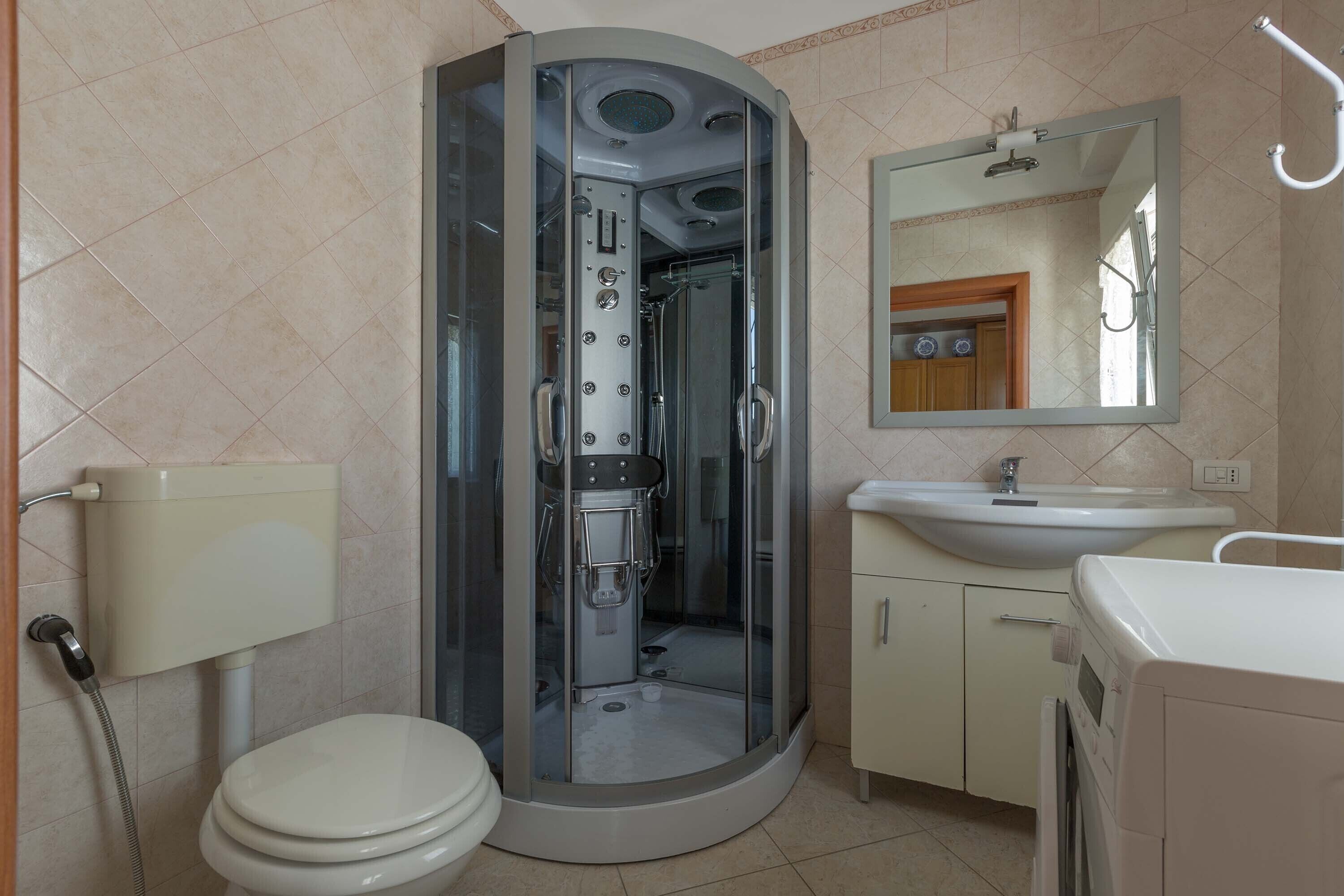 Une salle de bain avec une douche à parois de verre, des toilettes, un lavabo et un miroir.