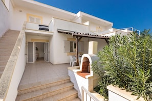 A two-story building with a staircase leading to a covered outdoor area. - Solemare (Ugento)