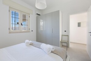 A bedroom with a bed, a wardrobe, a chair, and a window. - Villa Diamante (Maruggio)