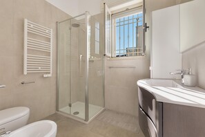 A modern bathroom with a glass-enclosed shower, a white sink, and a toilet. - Villa Diamante (Maruggio)