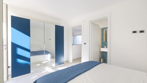 Une chambre à coucher moderne, dotée d’un grand lit, d’un dressing et d’une salle de bain visible à travers une porte ouverte.