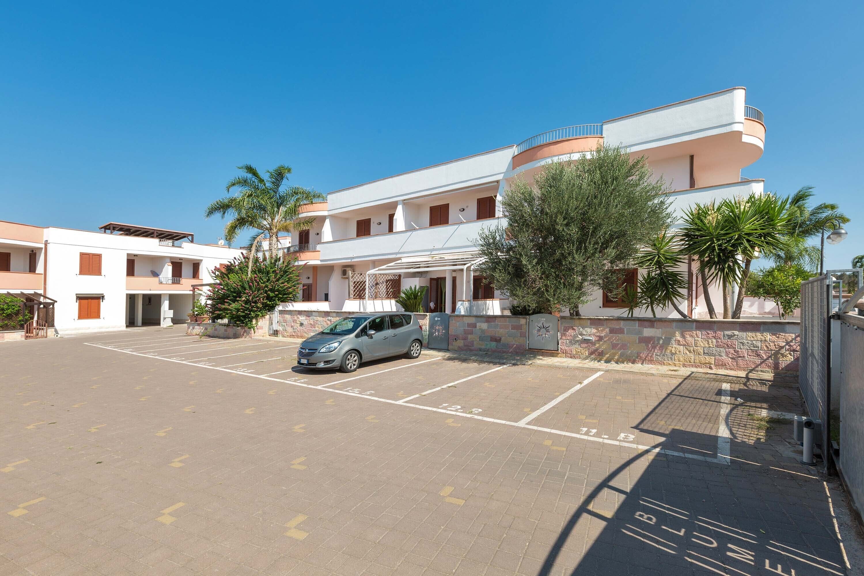 A multi-story building with a parking area in front.