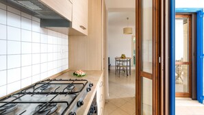 A modern kitchen with a gas stove, wooden cabinets, and a view into a dining area.