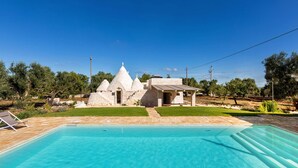 A swimming pool with a stone house in the background. - Trullo Giamar (Ostuni)