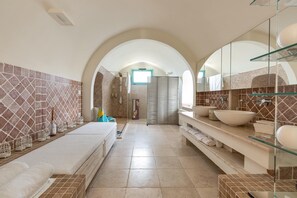 A modern bathroom with a large mirror, a glass shower enclosure, and a vanity with a large bowl sink.