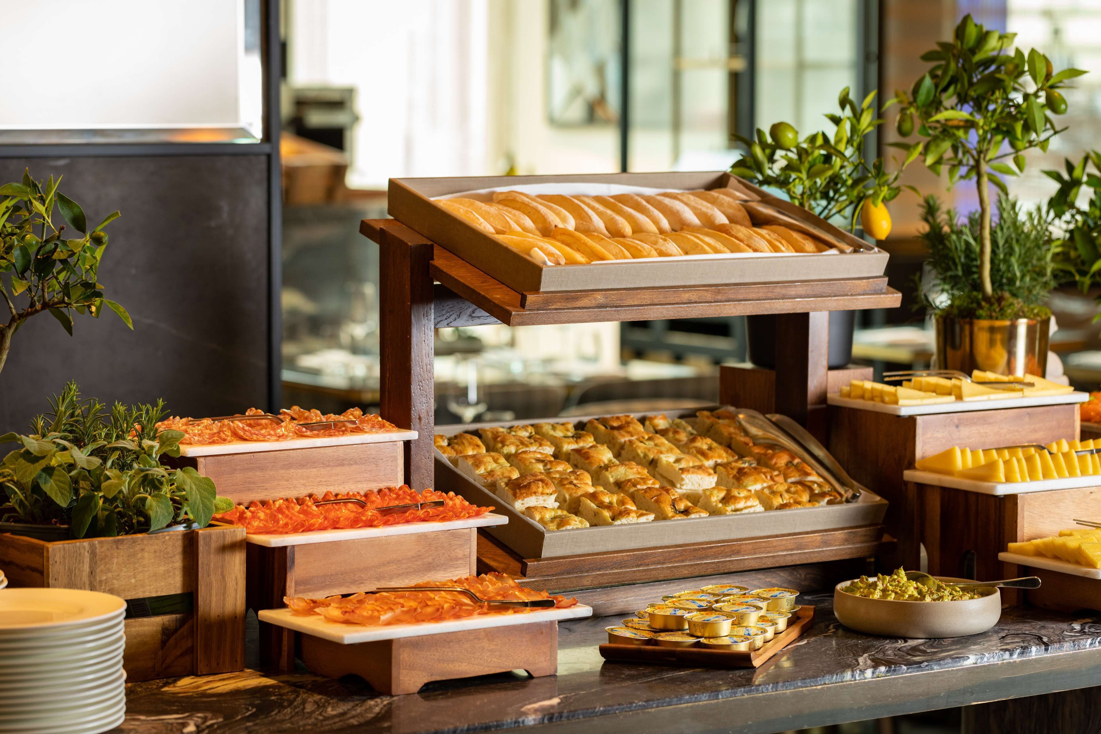 Buffet com diversos alimentos, incluindo pães, doces e saladas.