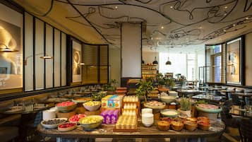 A buffet setup with various food items and beverages, surrounded by seating areas and a modern interior design.