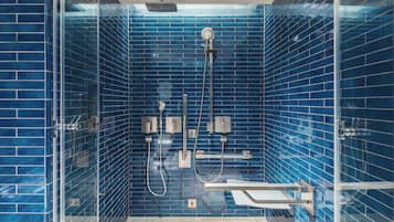 Een moderne badkamer met blauwe betegelde wanden, een douche met glazen wanden en een witte wastafel.