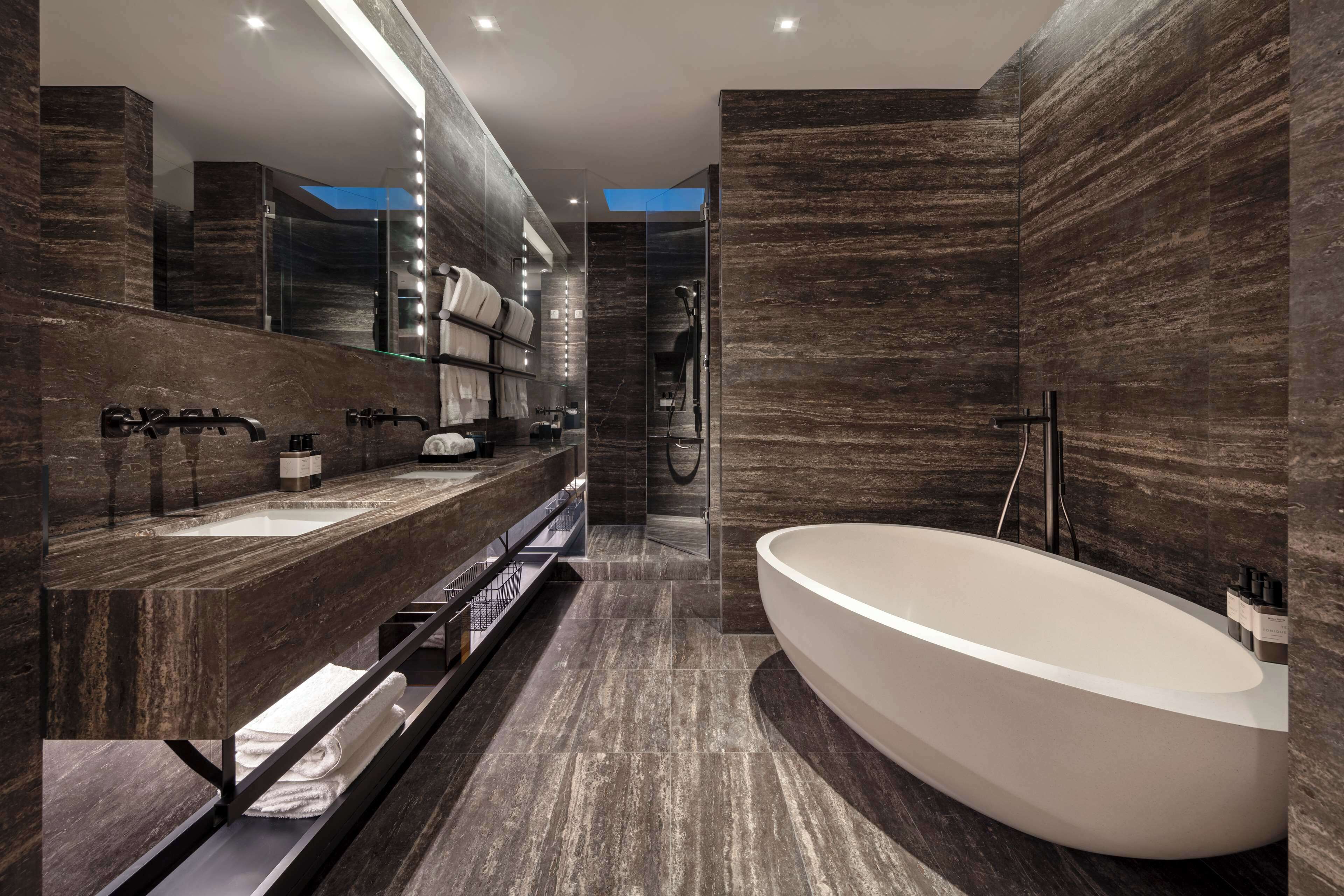 A modern bathroom with a large bathtub, a double sink vanity, and a walk-in shower.