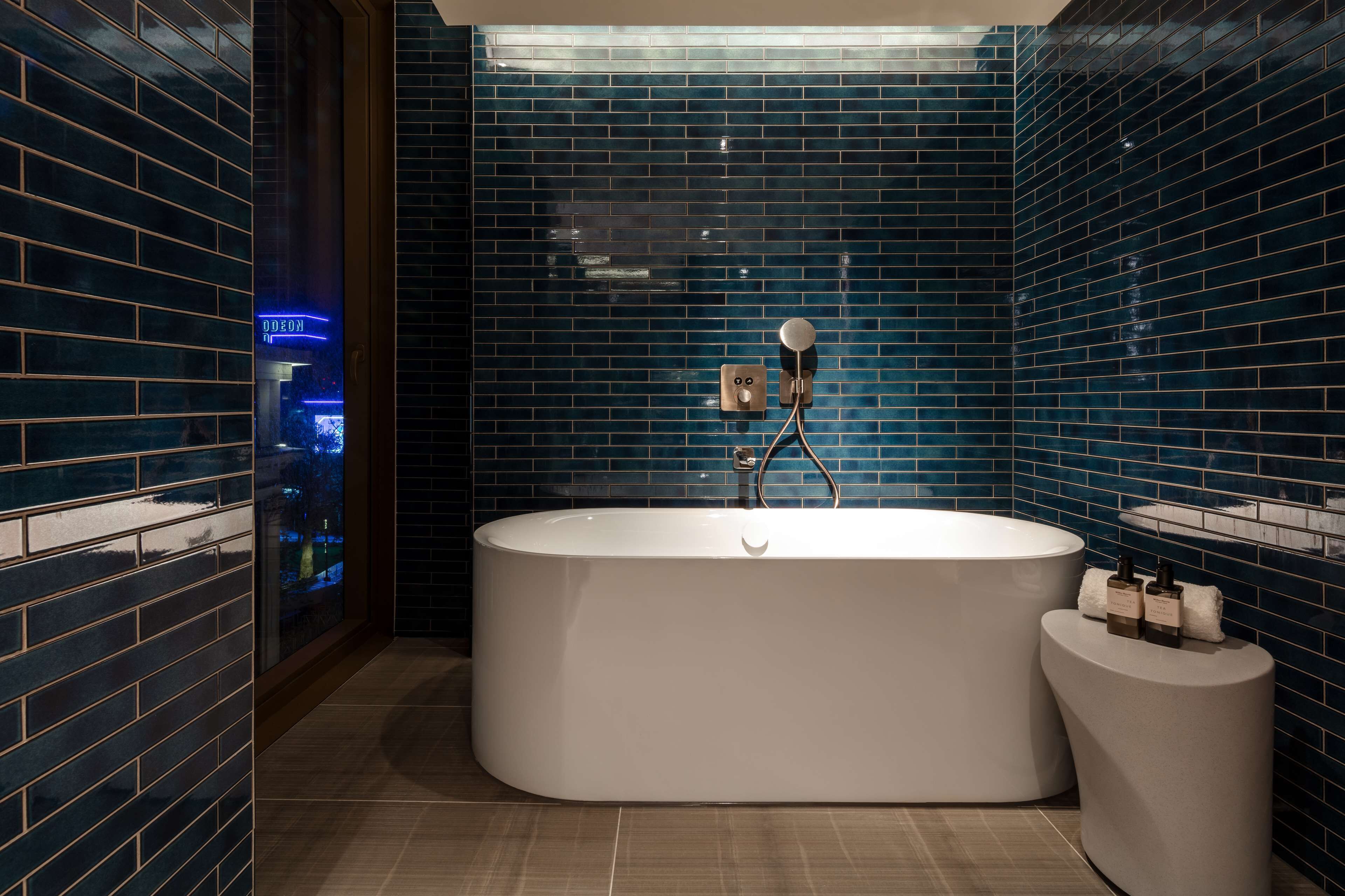 A modern bathroom with a freestanding bathtub, a glass shower enclosure, and a small vanity with toiletries.