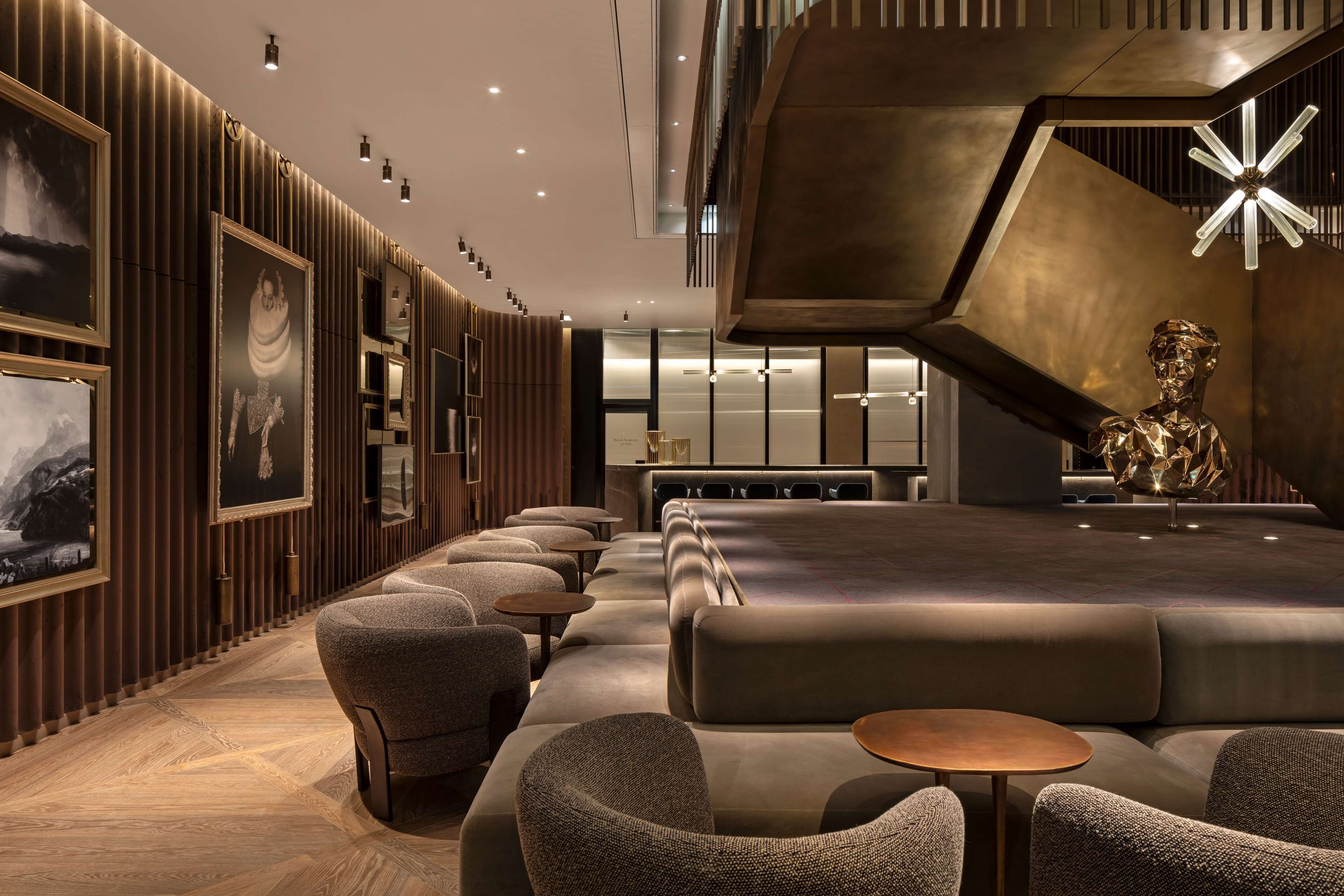 A modern hotel lobby with a central seating area, framed artwork on the walls, and a unique geometric light fixture.