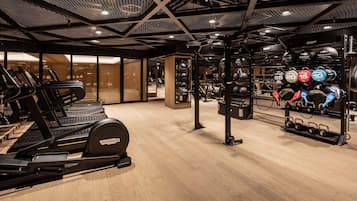 Une salle de sport équipée de tapis de course, de matériel de musculation et d’une variété d’haltères.