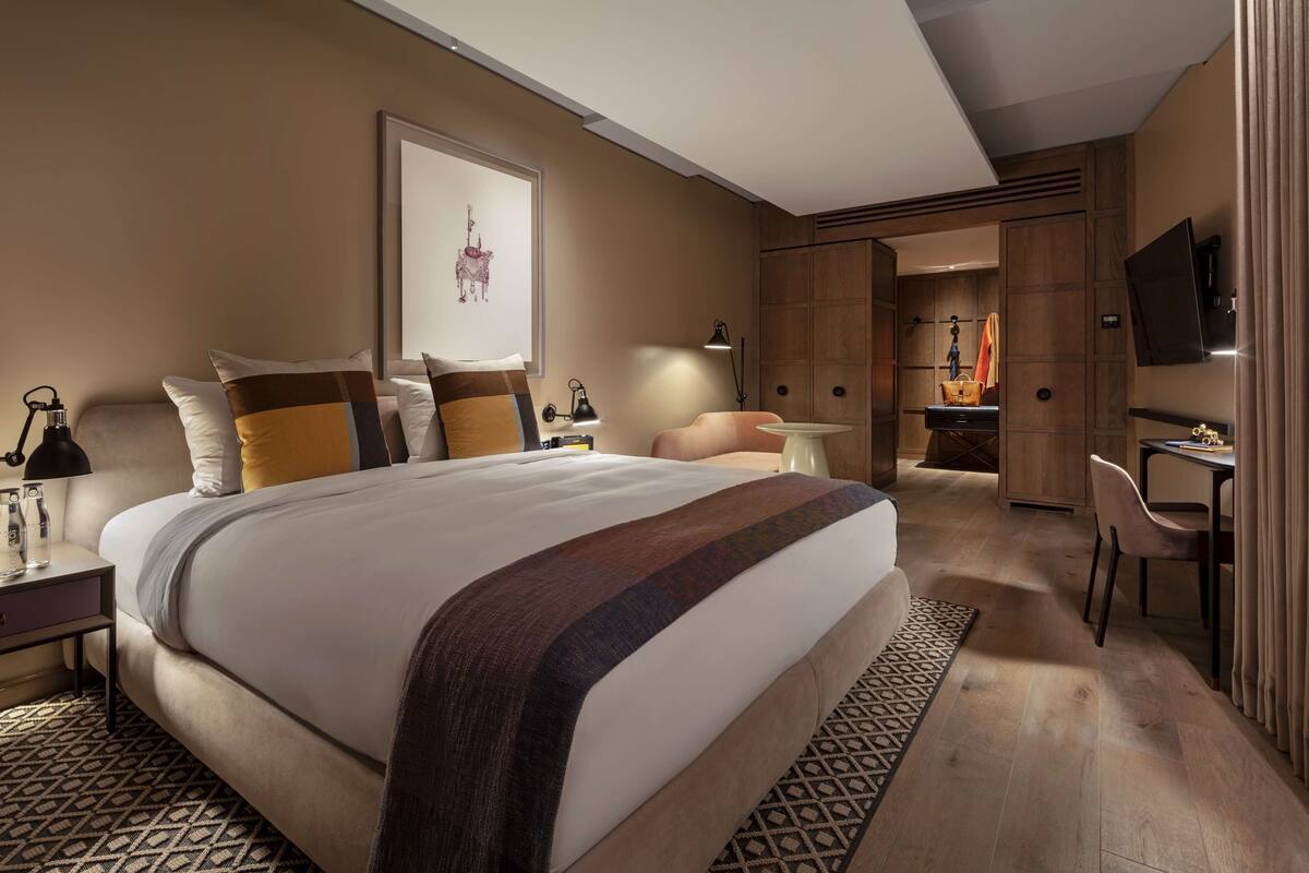 A modern hotel room with a large bed, bedside tables, a desk, and a TV.