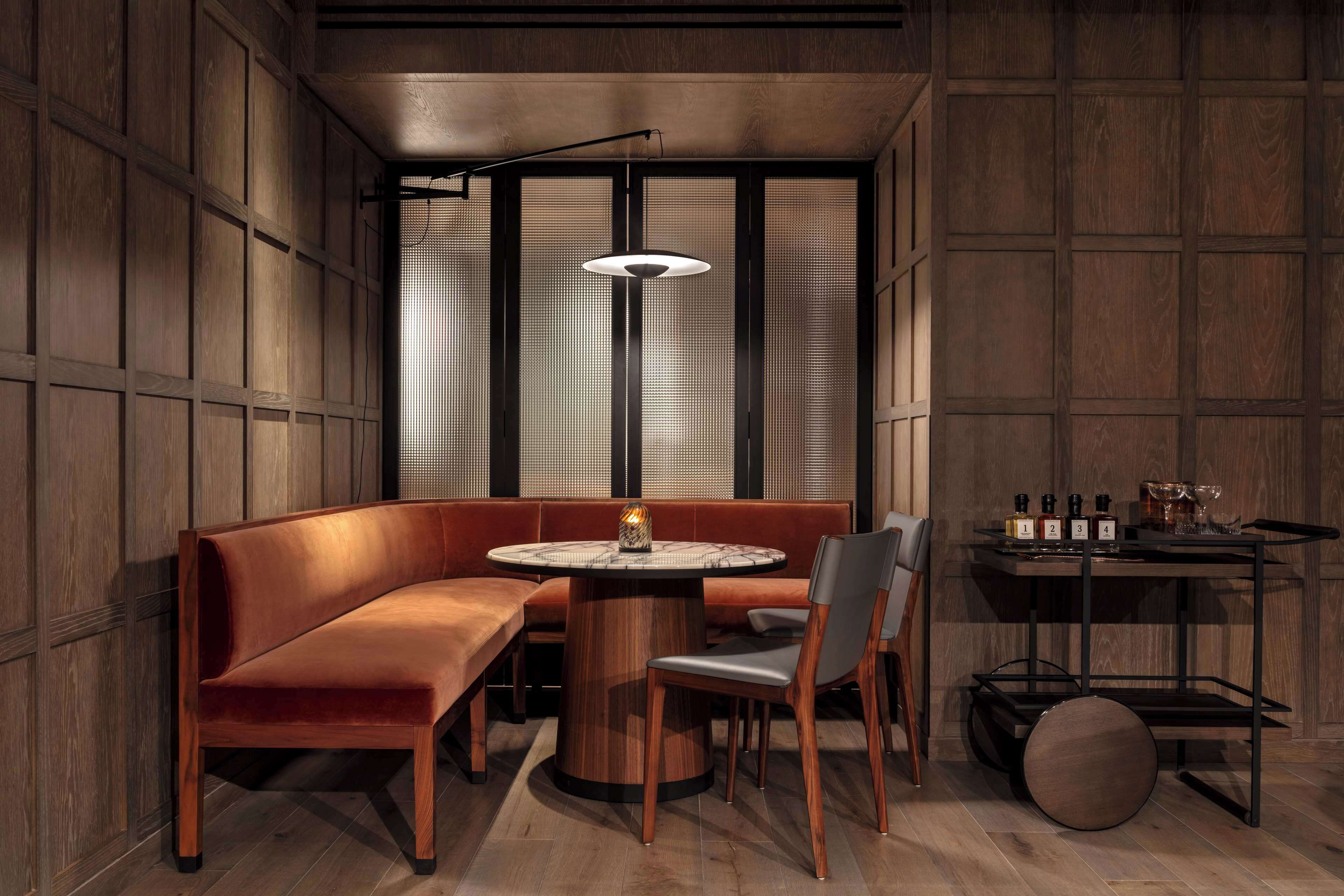 A cozy seating area with a round table, cushioned benches, and a pendant light.