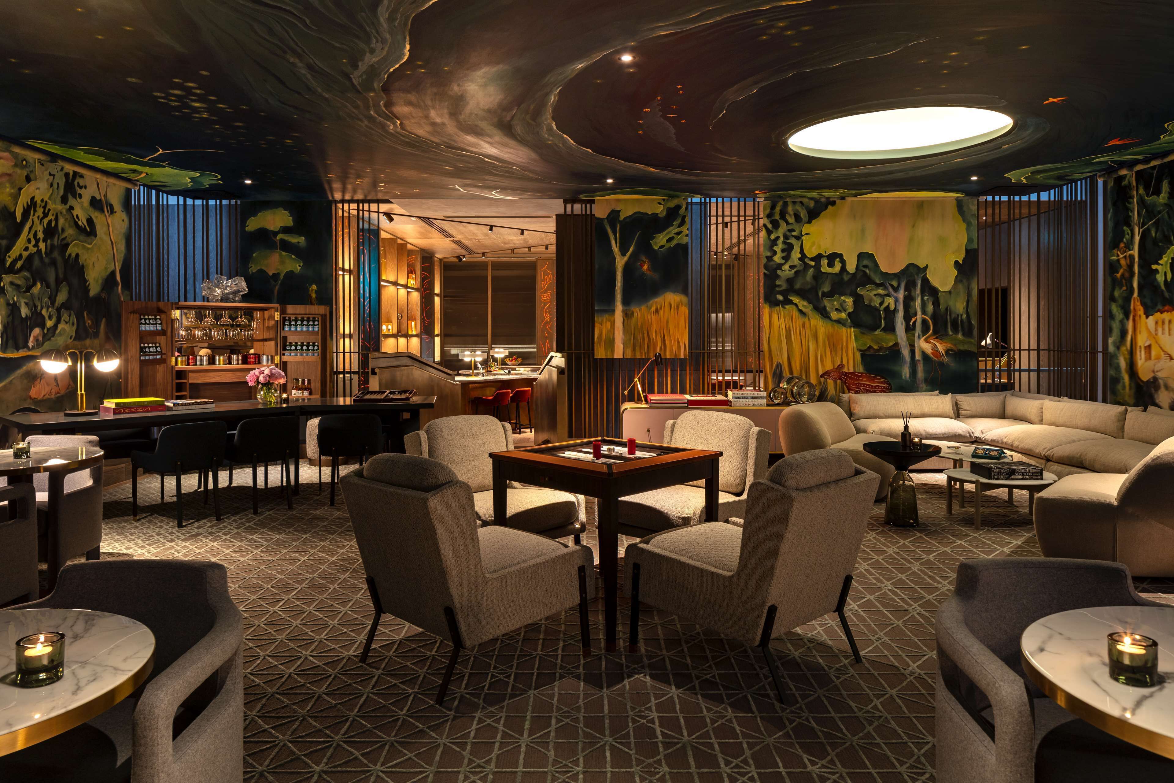 A modern lounge area with a bar, seating, and a mural.