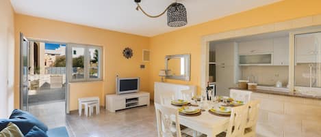 A compact living space with a dining area, kitchenette, and a TV.