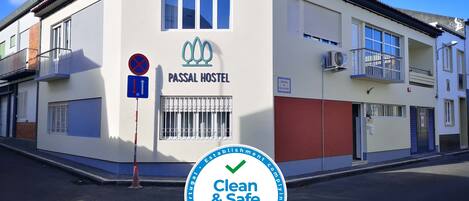 A building with a sign reading "PASSAL HOSTEL" and a "Clean & Safe" certification badge.