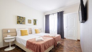 A hotel room with two beds, a bedside table, a flat-screen TV, and artwork on the wall. - Passal Hostel (Ponta Delgada)