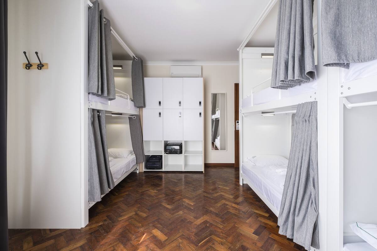A compact room with bunk beds, a wardrobe, and a mirror.