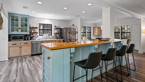 Una cocina moderna con una isla central, taburetes de bar y vistas al área de comedor contigua.