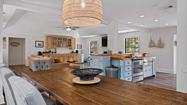 A spacious kitchen with wooden cabinets, a dining area with a large wooden table, and a hanging light fixture.