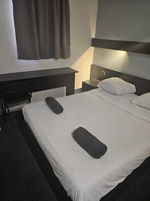 Una habitación de hotel con una cama, un escritorio y una silla.