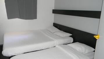 A single bed with white bedding in a room with a dark headboard and a gray curtain.