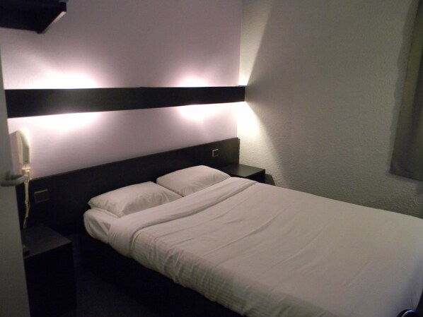 A single bed with a headboard, two bedside tables, and a wall-mounted phone. - Class Hôtel Poitiers (Poitiers)