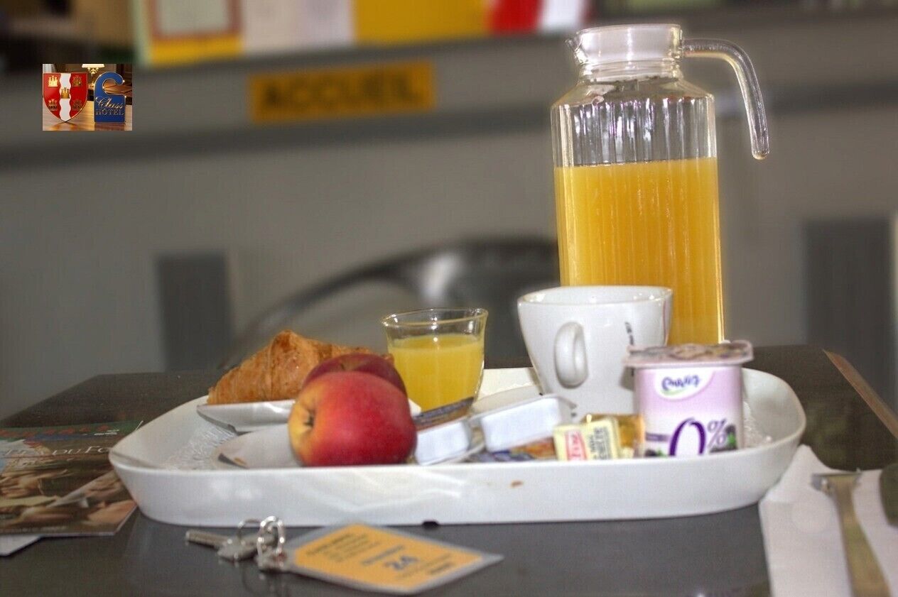 A breakfast tray with a croissant, peach, juice, a mug, and a container of yogurt.