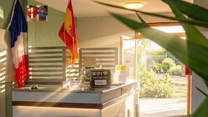 Mostrador de recepción con un cartel que indica la contraseña del WiFi, banderas y vistas al exterior.