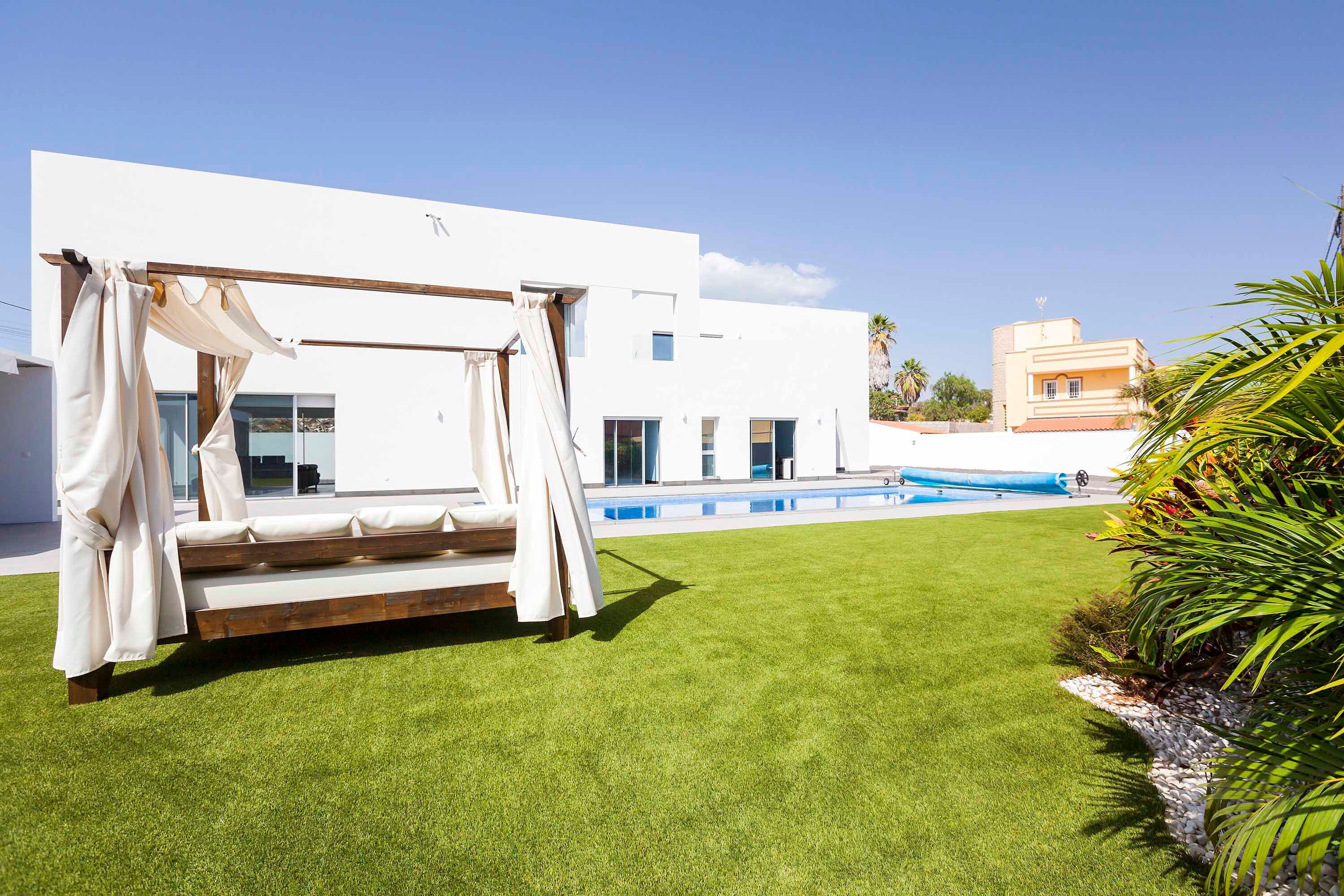 A modern outdoor area with a white building, a pool, and a wooden bench.