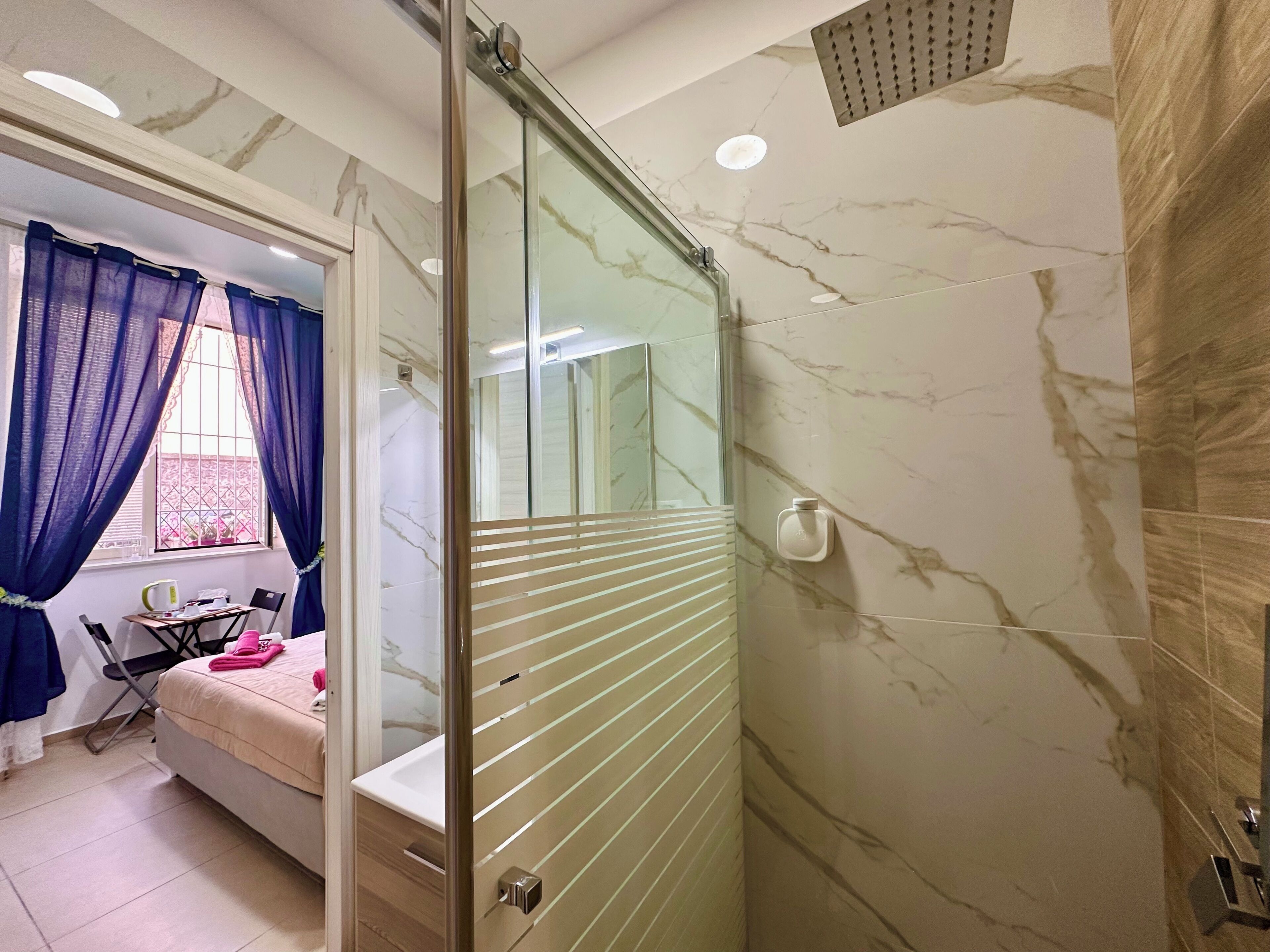 A bathroom with a glass shower door, a sink, and a mirror.