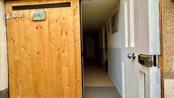 A wooden door with "B&B" and "Sweet Dreams" signs, a hallway with a tiled floor, and a door with a lock and a device attached.