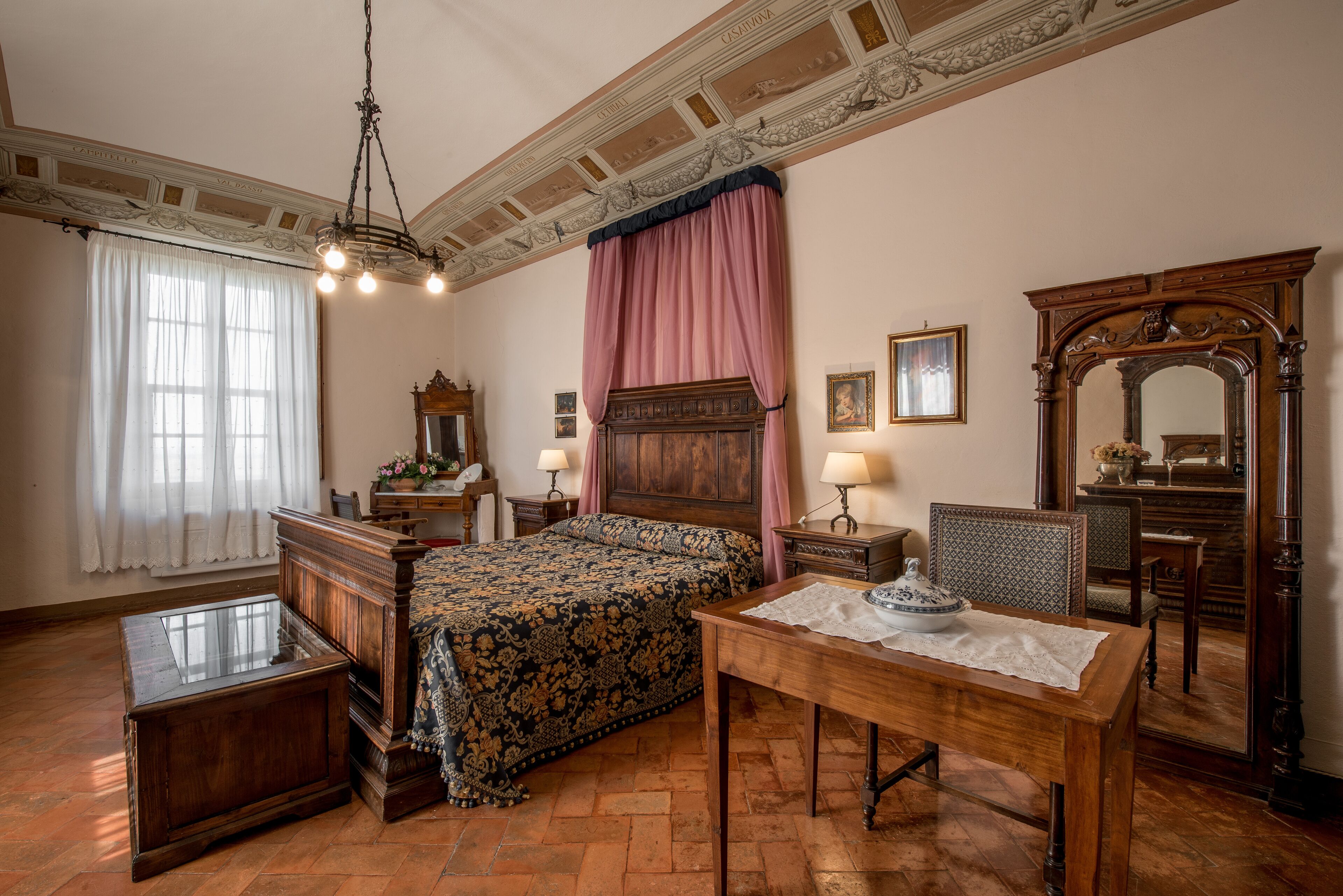 A traditional bedroom with a four-poster bed, a wooden nightstand, a table with a vase, and a mirror.