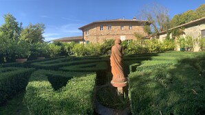 A statue in a garden with a stone building in the background. - Agriturismo Fattoria Del Colle (Trequanda)